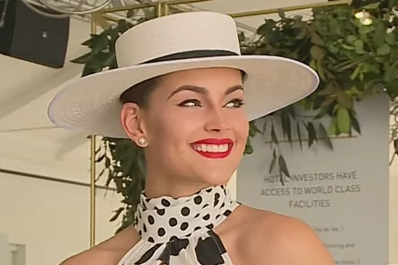 Rolene Strauss en robe à pois, chapeau blanc et rouge à lèvres vif lors d'un événement de polo