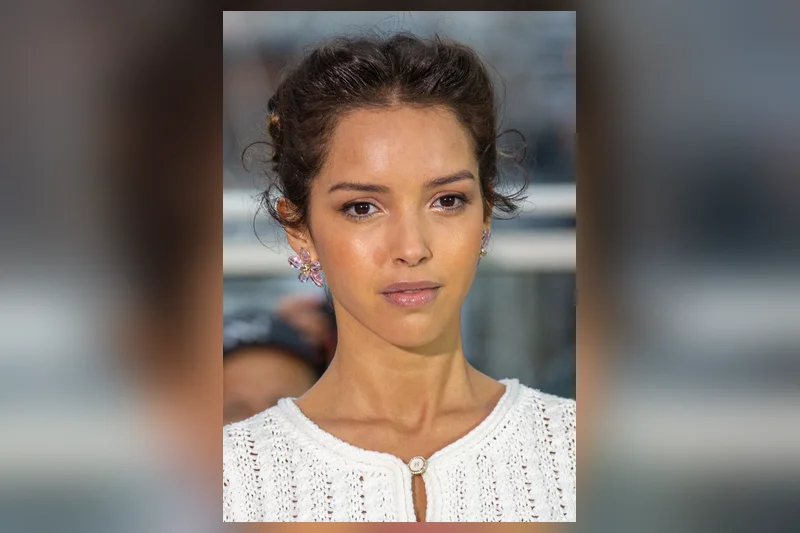 Lyna Khoudri en haut blanc brodé, cheveux relevés et boucles d'oreilles à Cannes