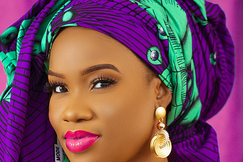 Faty en portrait studio avec foulard violet et vert, robe turquoise et bijoux dores
