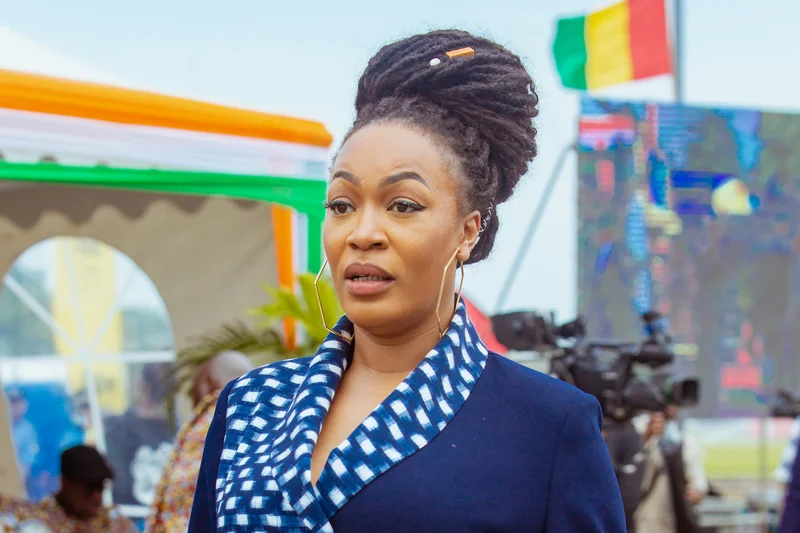 Josey en tenue bleue a motif blanc avec chignon tresse et accessoires dores lors d'un evenement