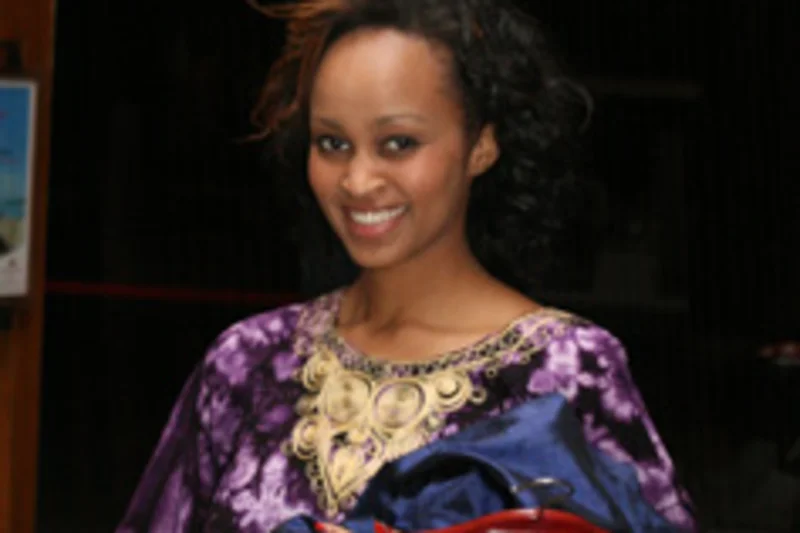Catherine Wainaina souriante en tenue violette et doree lors d'un evenement Miss Kenya