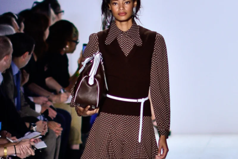 Malaika Firth defilant en robe brune a pois sur un podium Michael Kors
