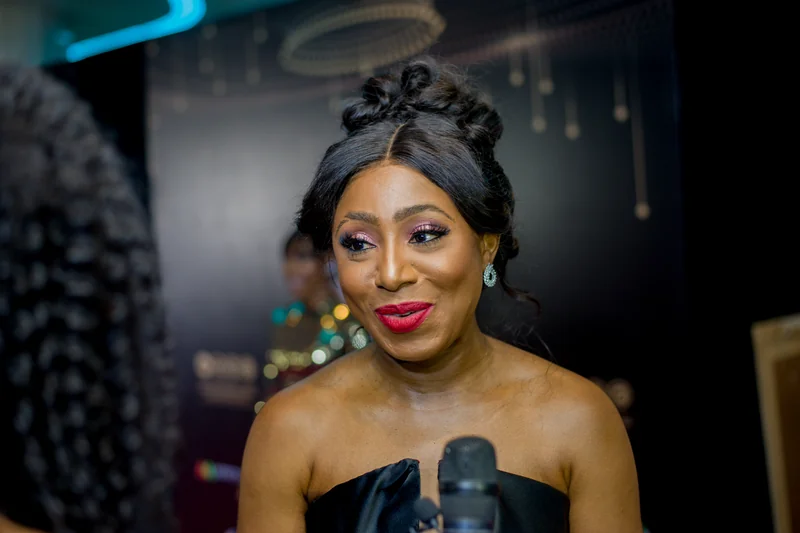 Dakore Akande en portrait de ceremonie avec robe noire, maquillage rose et coiffure relevee