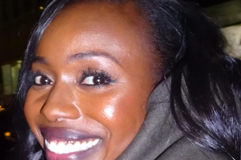 Anna Diop souriante en portrait rapproché avec cheveux noirs et lumière de soirée