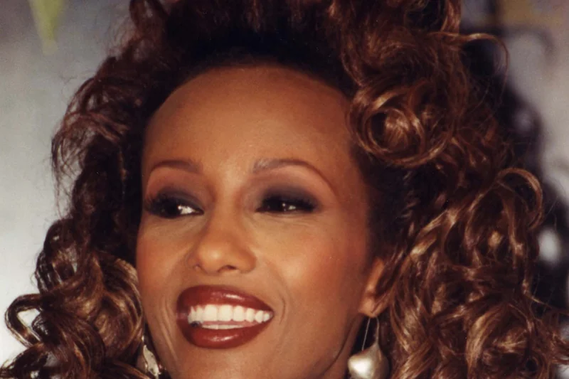 Iman en portrait beaute avec cheveux volumineux et boucles d'oreilles brillantes