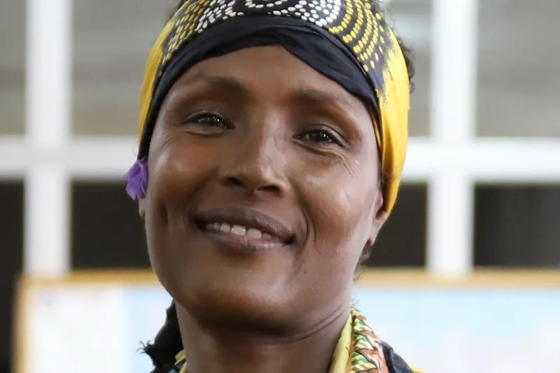 Waris Dirie souriante avec foulard imprime jaune et noir et vetement traditionnel colore
