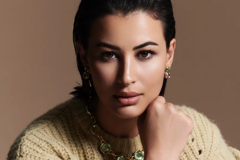 Rym Saidi en portrait studio avec pull clair, cheveux noirs attachés et regard direct